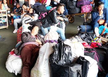Durmiendo sobre maletas esperan un  pasaje en el terminal de San Cristóbal