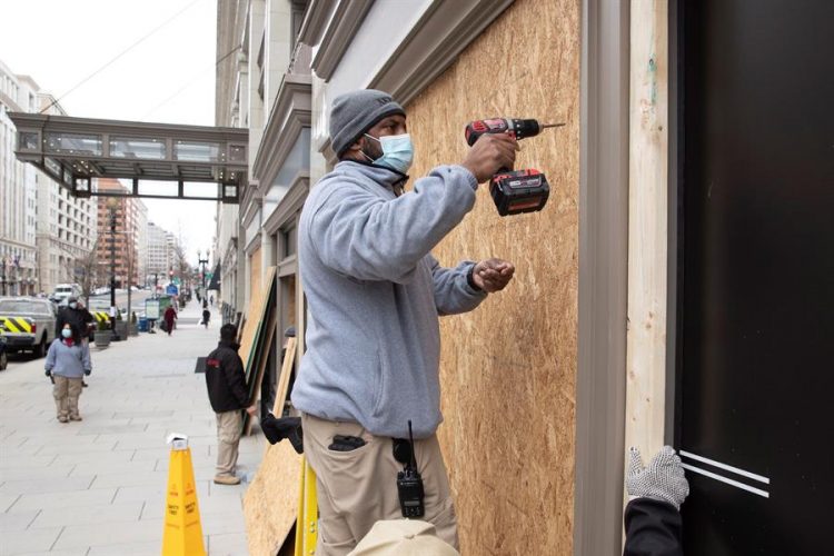 Obreros fueron registrados este lunes al cubrir con láminas de madera los cristales de tiendas comericales, antes de la manifestación de apoyo al saliente presidente Donald Trump, en Washington DC (EE.UU.) EFE/Michael Reynolds