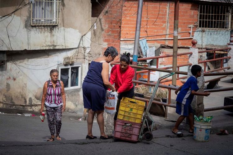 Alexandra Armijo (c), de 22 años, cambia plátanos por arroz en un barrio de Catia, el 20 de enero de 2021 en Caracas (Venezuela). EFE/Rayner Peña R.