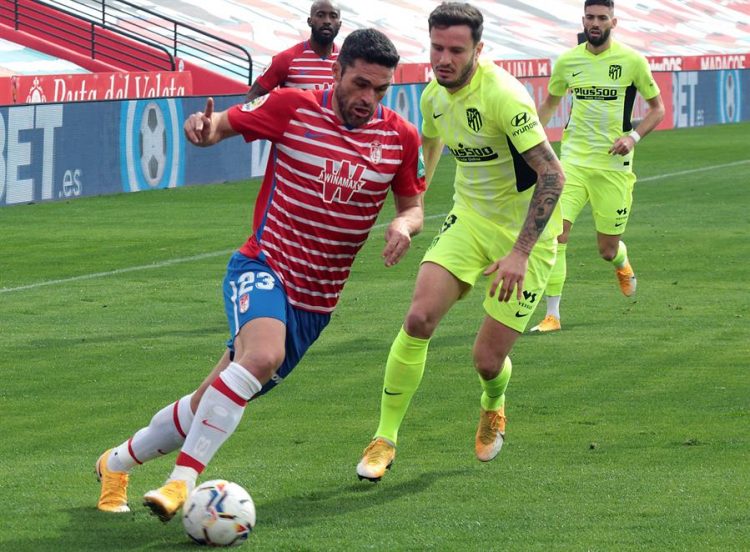 El delantero del Granada Jorge Molina (i) con el baón ante el centrocampista del Atlético de Madrid, Saúl Ñíguez (d) durante el partido de LaLiga Santander, jornada 23,