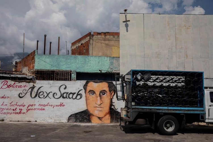Un pequeño camión pasa junto a un grafiti con la imagen del rostro de Alex Saab en Caracas (Venezuela). EFE