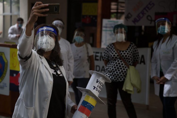 Fotografía del 13 de abril del 2021 donde se observa a un médico revisar su teléfono celular durante una protesta por vacunas contra el COVID-19 en Caracas (Venezuela). EFE/Miguel Gutiérrez