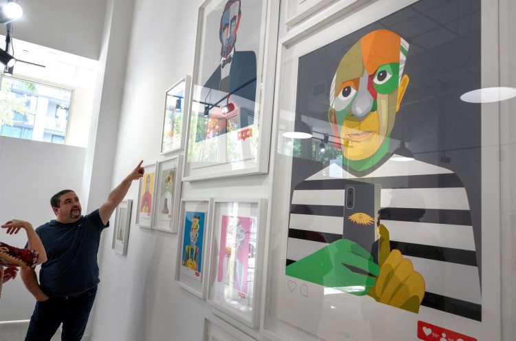 El artista venezolano Eduardo Sanabria señala una de las piezas de su colección 'Selfish' durante la vista previa de su exposición 'Edo Love Pop. Next Level 'en el Doral Contemporary Art Museum