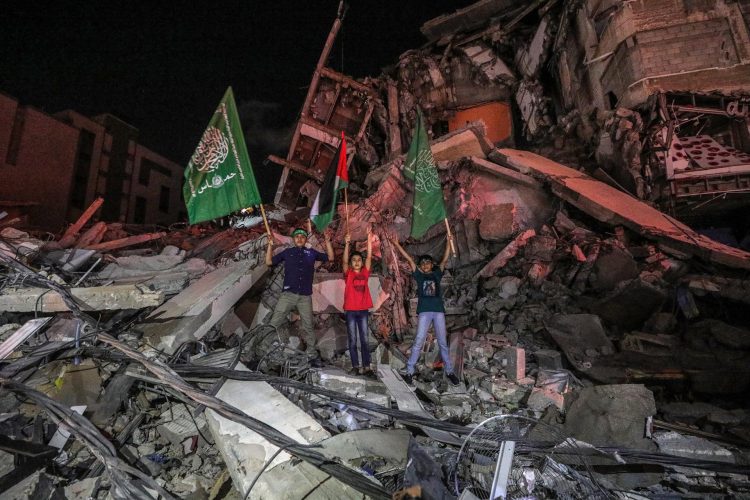 Palestinos celebran la tregua entre Israel y las milicias palestinas, en medio de los escombros de un edificio en la ciudad de Gaza. EFE/