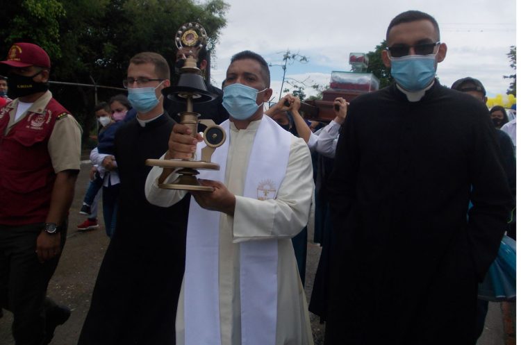 El padre Magdaleno Álvarez muestra la reliquia en alto al entrar al poblado