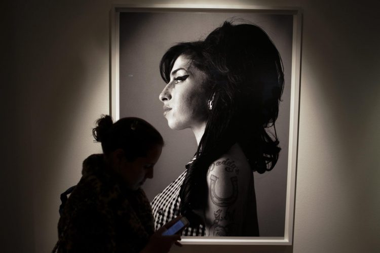 Un visitante pasa frente a un retrato de la fallecida cantante británica Amy Winehouse hecho por el cantante y compositor canadiense Bryan Adams. EFE/PEDRO FREITAS SILVA/Archivo