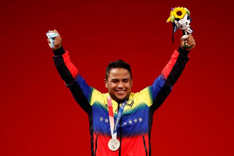 El venezolano Keydomar Giovanni Vallenilla Sanchez celebra en el podio tras conseguir la medalla de plata en la prueba de levantamiento de pesas masculino de 96 kg durante los Juegos Olímpicos 2020, este sábado en el Foro Internacional de Tokio (Japón). EFE/José Méndez