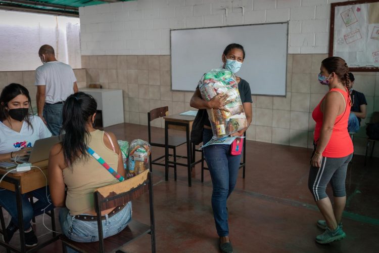 Johangely Crespo carga una bolsa de comida durante una jornada de entrega de donativos de Acción por Venezuela para familias vulnerables de barrio Cota 905, el 17 de septiembre, en Caracas (Venezuela). EFE/Rayner Peña R