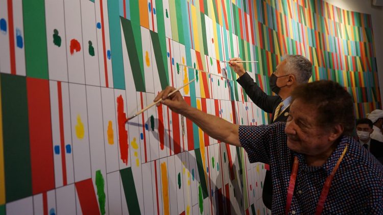 El artista Juvenal Ravelo, acompañado por el ministro de Turismo de Venezuela, Alí Padrón, ayuda a terminar un gran mural que decora el pabellón venezolano, dentro de las celebraciones del día nacional del país latinoamericano en la Expo de Dubái. EFE/ Iñigo Álvarez