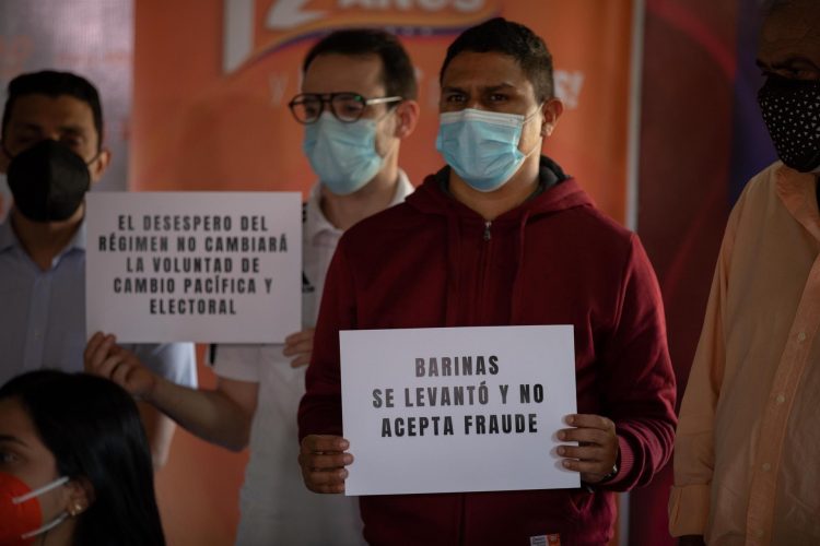 Opositores sostienen pancartas en protesta contra la repetición de las elecciones en el Estado Barinas, el 06 de diciembre, Caracas (Venezuela). EFE/ RAYNER PEÑA R.