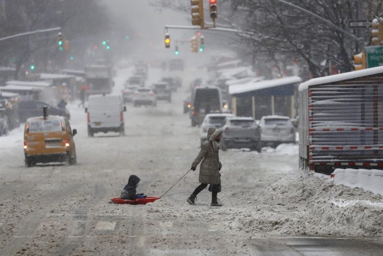 Una mujer y un niño sobre un trineo fueron registrados este sábado al cruzar una calle cubierta de nieve en Nueva York (NY, EE.UU.). EFE/Peter Foley