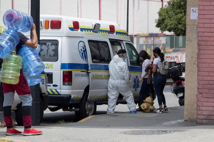 Un trabajador sanitario asiste a dos mujeres al ingresar a una ambulancia frente a la Clínica Popular de Catia en Caracas (Venezuela), en una fotografía de archivo. EFE/Rayner Peña R.