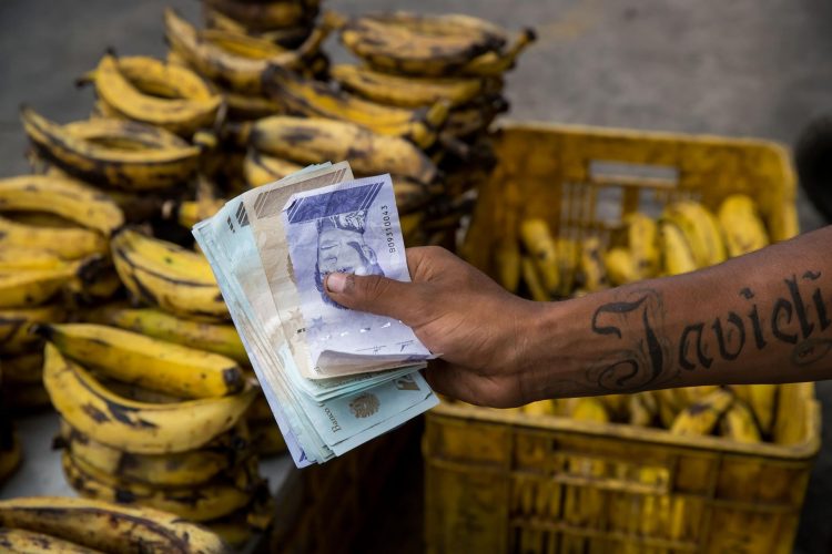 Fotografía fechada el 7 de febrero de 2022 donde se observa un vendedor ambulante mientras sostiene billetes de bolívares, en Caracas (Venezuela). EFE/Miguel Gutiérrez