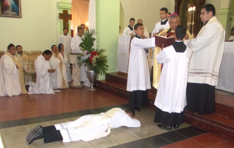 Tendido en las losas del templo San Juan Bautista el aún diácono Lenín García, mientras el obispo eleva una oración.