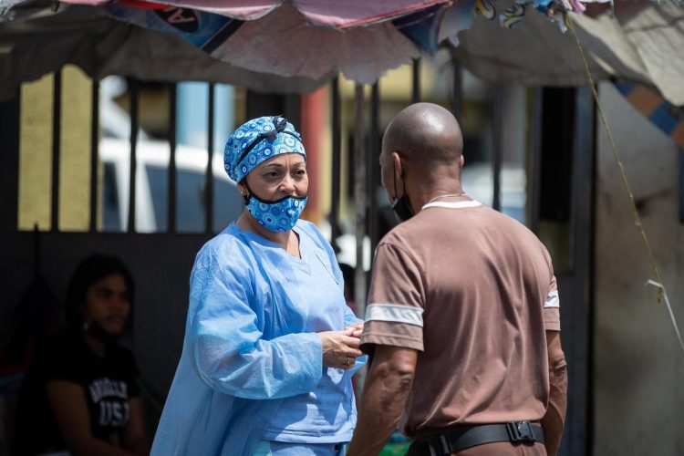 Fotografía de archivo de una trabajadora de la salud mientras habla con un hombre fuera del Hospital Periférico de Catiaen Caracas (Venezuela). EFE/ Rayner Peña R.