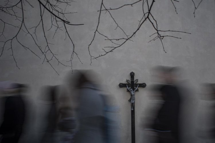 Fotografía hecha con velocidad de obturación lenta que muestra a creyentes caminando junto a una cruz, en foto de archivo. EFE/Martin Divisek