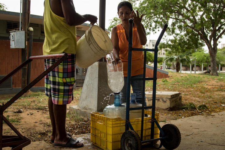 Personas usan recipientes plásticos para sacar agua de un pozo en una calle, el 12 de julio de 2022 en Maracaibo (Venezuela). EFE/ Henry Chirinos