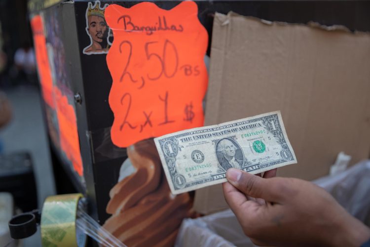 Un hombre muestra un billete de dólar en su puesto de venta de helados en Caracas (Venezuela). EFE/ RAYNER PEÑA R.