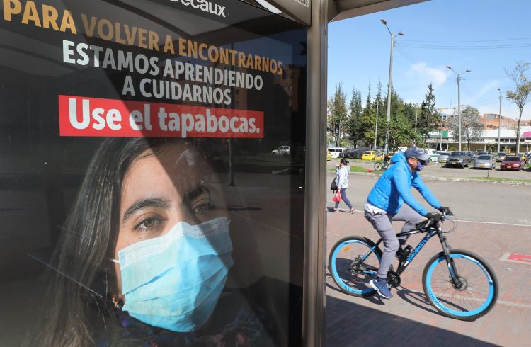 Un hombre circula en bicicleta junto a un anuncio que fomenta el uso del tapabocas en Bogotá, en una fotografía de archivo. EFE/Carlos Ortega