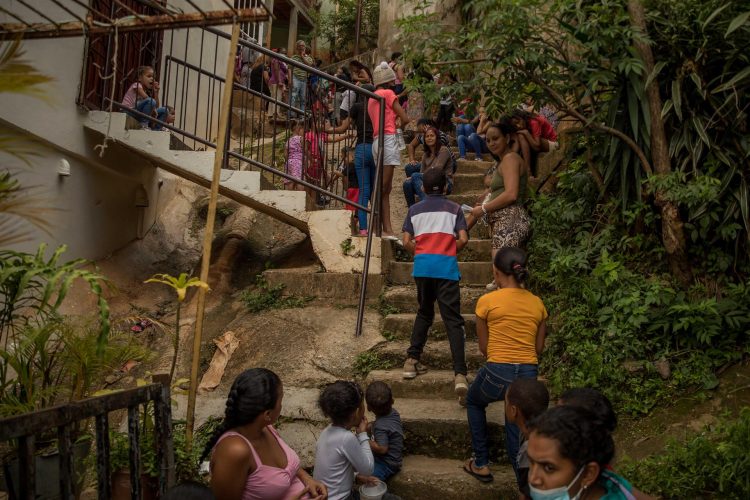 FotografÍa del 17 de agosto del 2022 donde se observa a un grupo de personas aguardar para recibir asistencia de la organización no gubernamental "Caritas", en un comedor de ayuda a personas con escasos recursos dentro de una barriada, en Caracas (Venezuela). EFE/ Miguel Gutiérrez