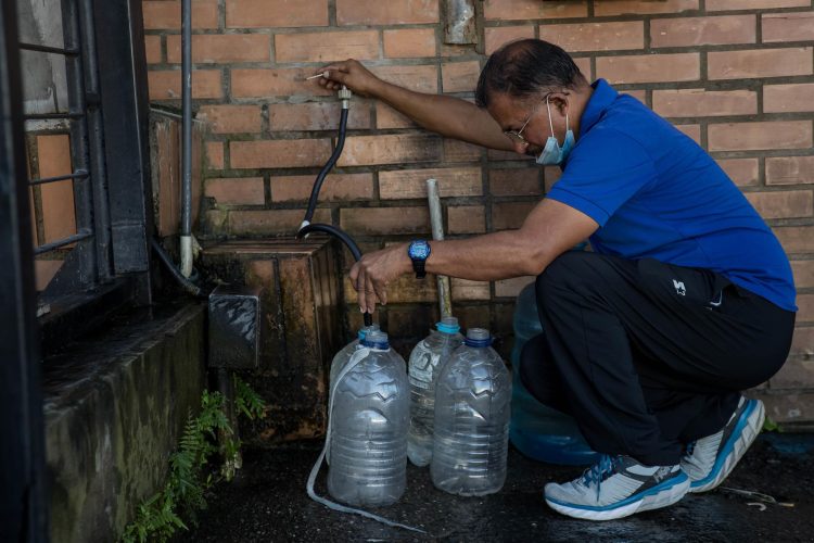 Un hombre recolecta agua potable en unos recipientes, el 12 de agosto de 2022, en Caracas (Venezuela). EFE/Miguel Gutiérrez