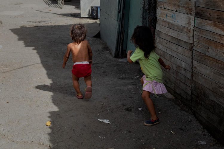 Fotografía de dos niños en viviendas improvisadas en un terreno ocupado en Caracas (Venezuela). EFE/Rayner Peña R.