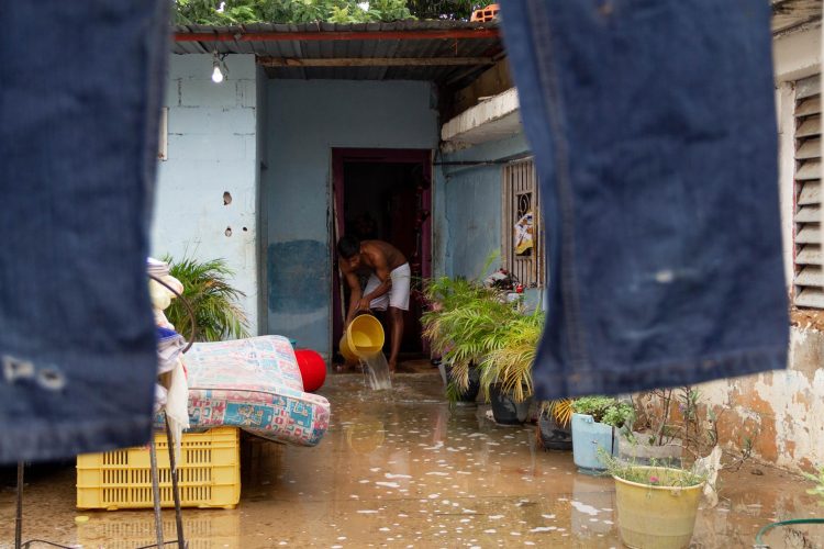 Un hombre saca agua de su casa inundada por la lluvia en una fotografía de archivo. EFE/Henry Chirinos