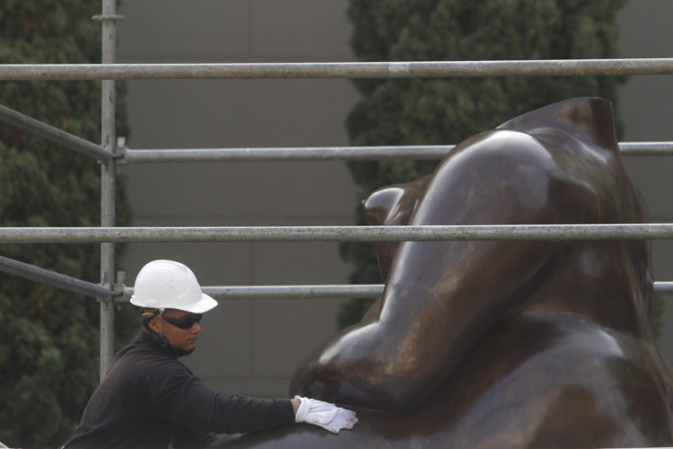 Un trabajador fue registrado este viernes, 17 de febrero, al limpiar una escultura del pintor y escultor colombiano Fernando Botero, en la Plaza Botero, en Medellín (Colombia). EFE/Luis Noriega