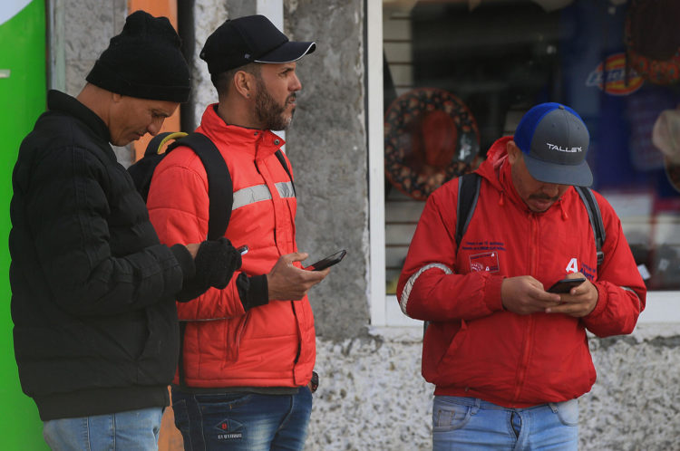 Fotografía de migrantes usando sus teléfonos móviles, el 18 de febrero de 2023, en Ciudad Juárez, Chihuahua (México). EFE/Luis Torres