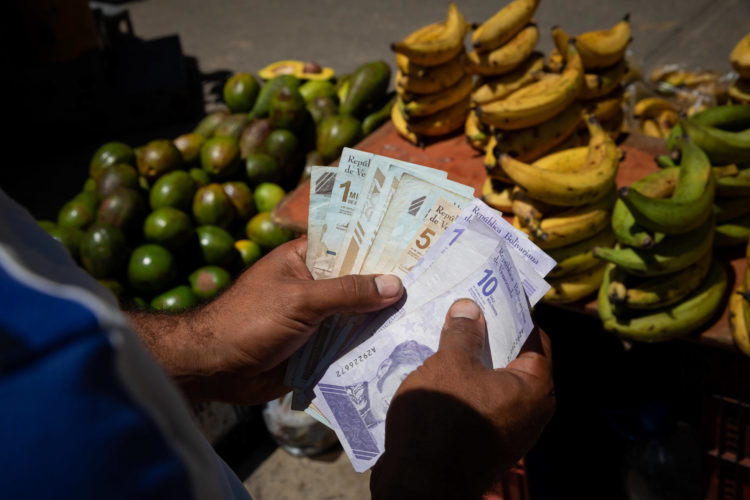 Un vendedor informal cuenta billetes de bolívar en un mercado de Caracas (Venezuela), en una fotografía de archivo. EFE/Rayner Peña R.
