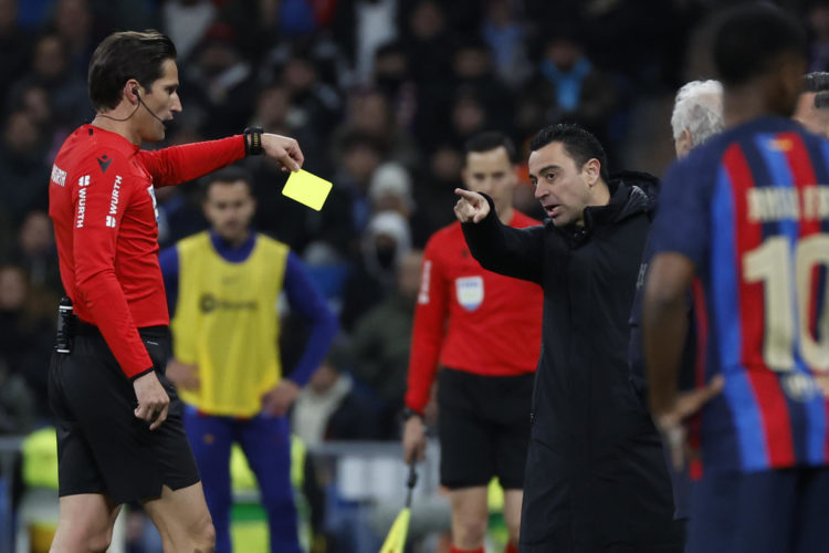 El colegiado Munuera Montero muestra tarjeta amarilla al técnico del FC Barcelona, Xavi Hernández, durante el encuentro correspondiente a la ida de las semifinales de la Copa del Rey que han disputado frente al Real Madrid en el estadio Santiago Bernabéu, en Madrid. EFE/Juanjo Martín.