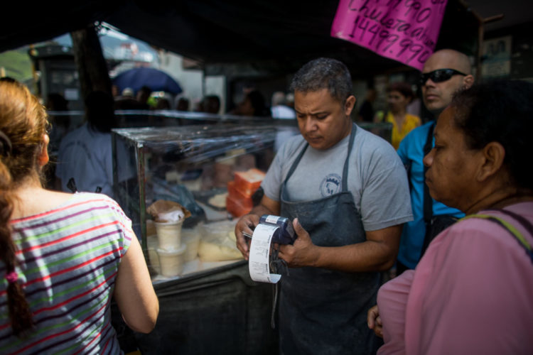 Fotografía de archivo en la que se registró a un tendero con un datáfono en un mercado callejero de alimentos, en Caracas (Venezuela). EFE/Miguel Gutiérrez