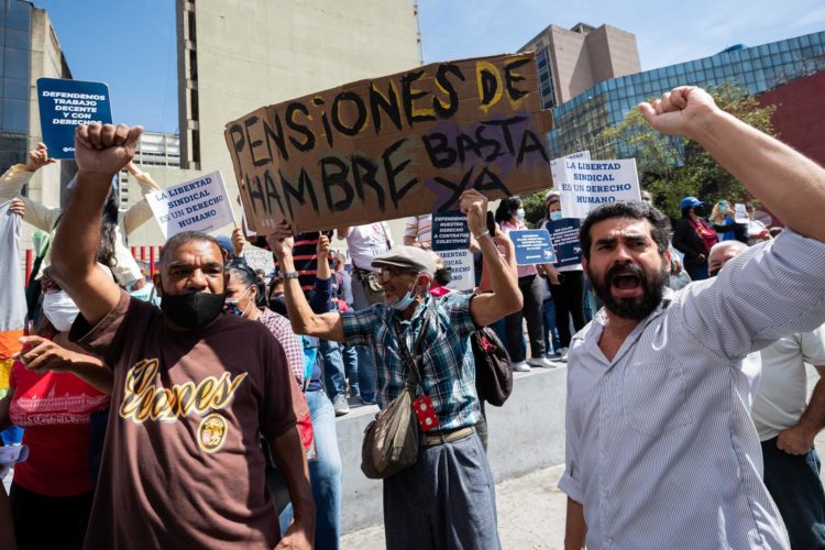 Un hombre carga una pancarta que dice "pensiones de hambre, basta ya", junto a trabajadores del sector salud participan en una manifestación para exigir mejores condicIones laborales y salariales en Caracas, en una fotografía de archivo. EFE/Rayner Peña R.