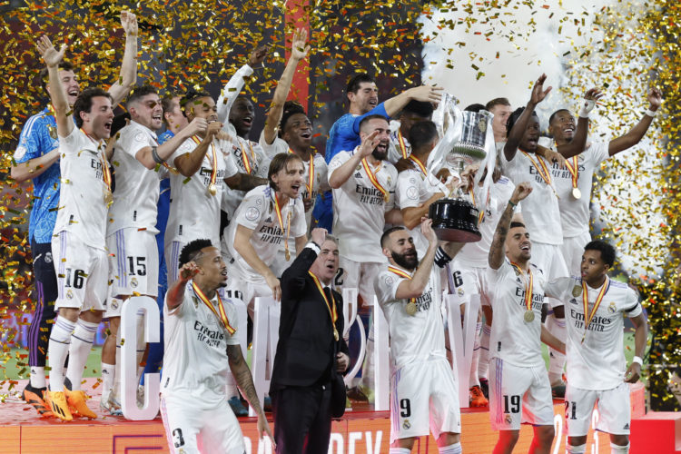 El capitán del Real Madrid, Karim Benzema (c-abajo) levanta junto a sus compañeros y al técnico italiano Carlo Ancelotti (2i-abajo), la Copa de S.M. El Rey entregada por Felipe VI tras vencer 2-1 a Osasuna en la final de la Copa del Rey de fútbol en el estadio de La Cartuja de Sevilla. EFE/ Julio Munoz