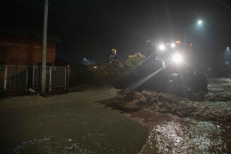 Bomberos pasan hoy sobre retroexcavadoras por calles anegadas por agua, causadas por la crecida del río Cachapoal, producto de las intensas lluvias en la comuna de Coltauco (Chile). EFE / Rafael Arancibia