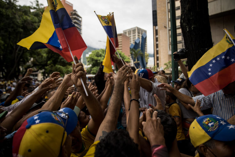 Fotografía de archivo fechada el 24 de junio del 2023 personas mientras sostienen banderas de Venezuela en un acto político, en Caracas (Venezuela). EFE/Miguel Gutiérrez