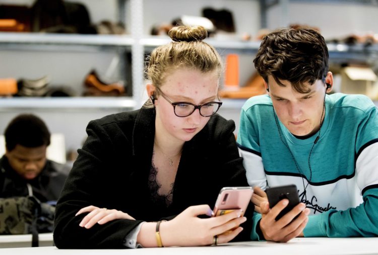 Estudiantes prestan atención a sus teléfonos móviles, en una fotografía de archivo. EFE/ Koen Van Weel