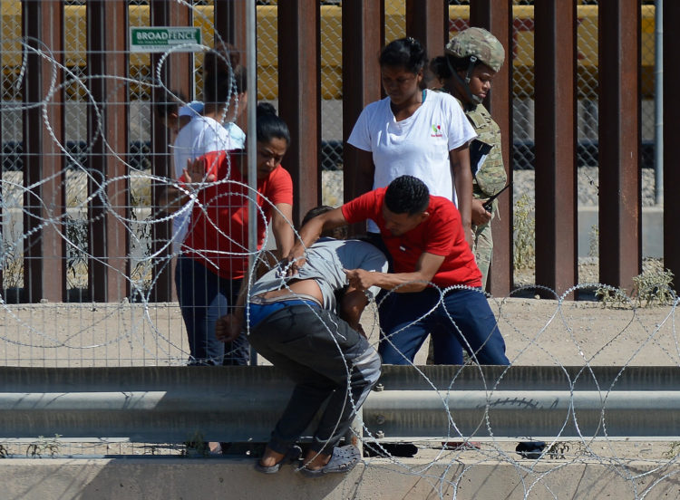 Migrantes cruzan las alambradas con filosas cuchilas colocadas en los muros hoy para entregarse a las autoridades y pedir asilo en Ciudad Juárez, Chihuahua (México). EFE/Luis Torres