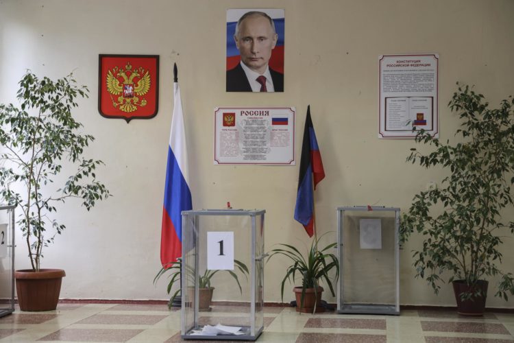 El escudo de armas de Rusia y un retrato del presidente ruso, Vladimir Putin, detrás de una urna durante las elecciones locales en Donetsk (Ucrania). EFE/EPA/STRINGER
