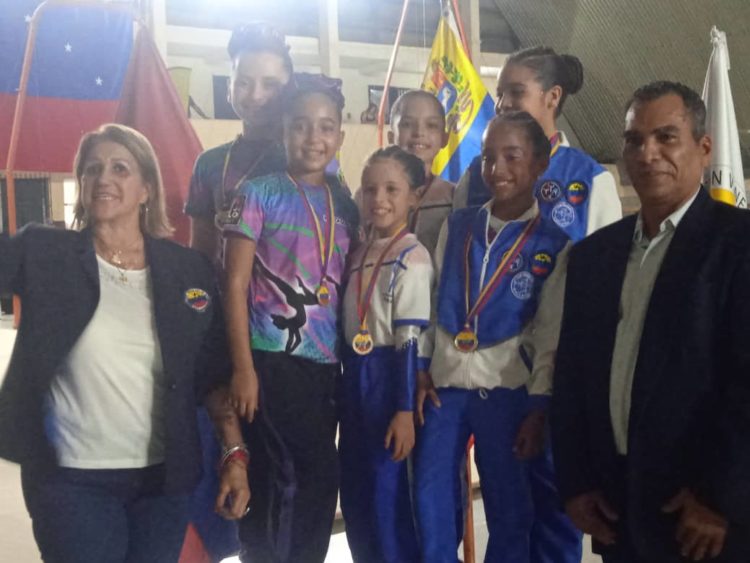 La pareja Naylick González y Luciana Luque reciben su presea de oro de parte de Zobeira Hernández, presidenta de la Federación Venezolana de Gimnasia  (Gráficas: Cortesía de Escuela de Gimnasia Valera)