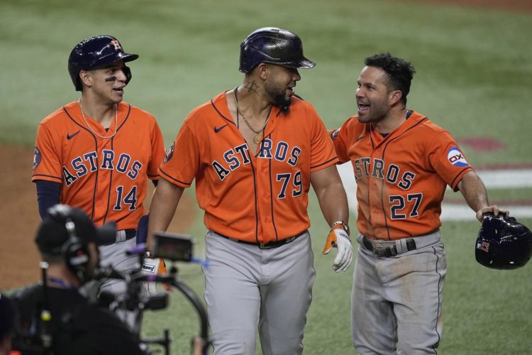 José Abreu (c) de los Astros de Houston es felicitado por sus compañeros Mauricio Dubon (i) y José Altuve (d) en el Globe Life Field, en Arlington, Texas (EE.UU.), este 19 de octubre de 2023. EFE/EPA/Kevin M. Cox