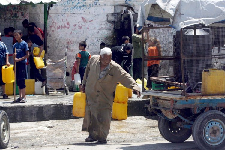 Imagen de archivo de un anciano palestino cargando con un bidón de agua tras llenarlo en una fuente en la Franja de Gaza. EFE/Mohammed Saber