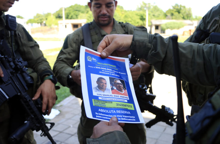 Un policía sostiene un cartel con la imagen de Luis Manuel Díaz, secuestrado por la guerrilla del ELN, hoy, en Barrancas (Colombia). EFE/ Ricardo Maldonado Rozo