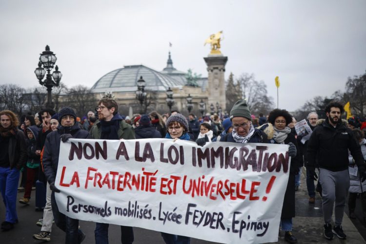 Manifestantes sostienen un pancarta durante la marcha de protesta celebrada en Paris contra la ley francesa sobre inmigración. EFE/EPA/Yoan Valat