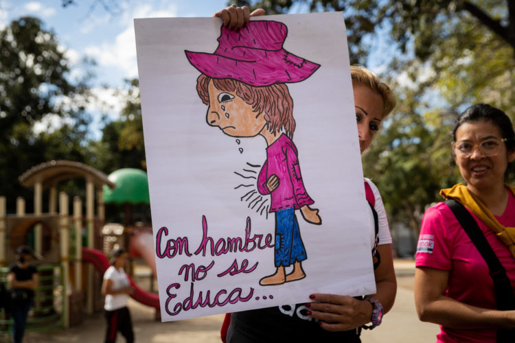 Una mujer sostiene una pancarta que dice "Con hambre no se educa" durante una protesta para exigir aumento salarial y de pensiones, hoy, en Caracas (Venezuela). EFE/Rayner Peña R.