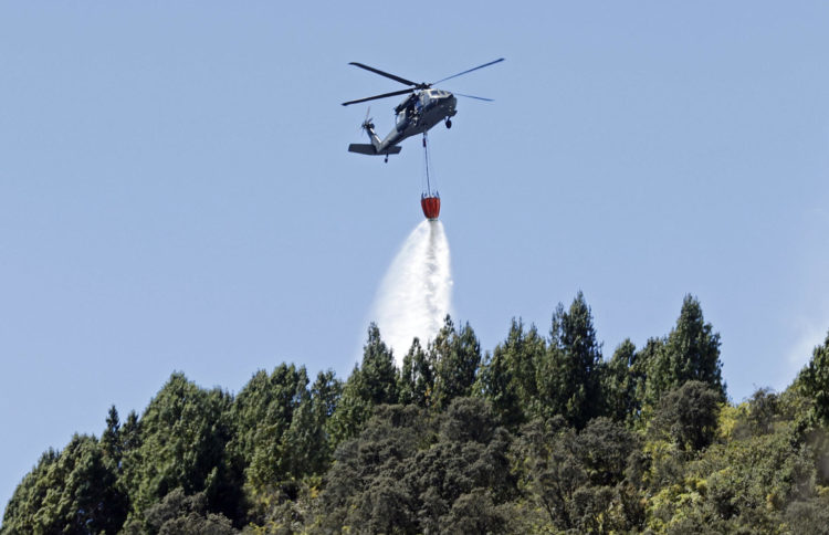 Un helicóptero del Ejército colombiano fue registrado este jueves, 25 de enero, al descargar agua sobre un incendio forestal, en el cerro El Cable, en Bogotá (Colombia). EFE/Mauricio Dueñas