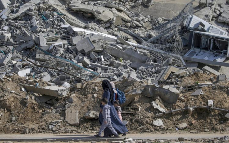 Una madre palestina camina con sus hijos junto a los escombros de un edificio residencial destruido en el campo de refugiados de Al Nuseirat, en el centro de la Franja de Gaza, tras los ataques aéreos israelíes, el 28 de febrero de 2024. EFE/EPA/MOHAMMED SABER