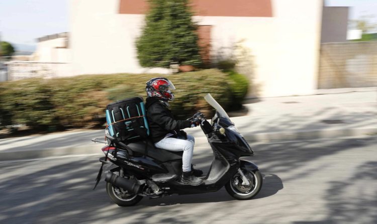 Un repartidor trabaja con su moto, en una fotografía de archivo. EFE/Zipi
