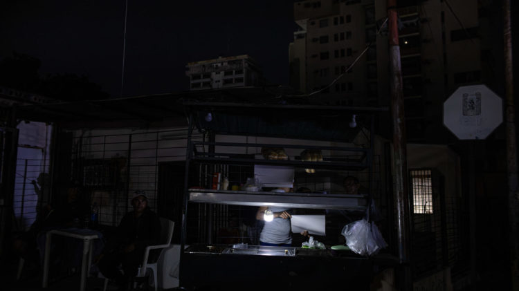 Una persona vende comida ayudado con un bombillo en medio de la oscuridad durante un corte eléctrico, el 29 de febrero de 2024 en Maracaibo (Venezuela). EFE/ Henry Chirinos