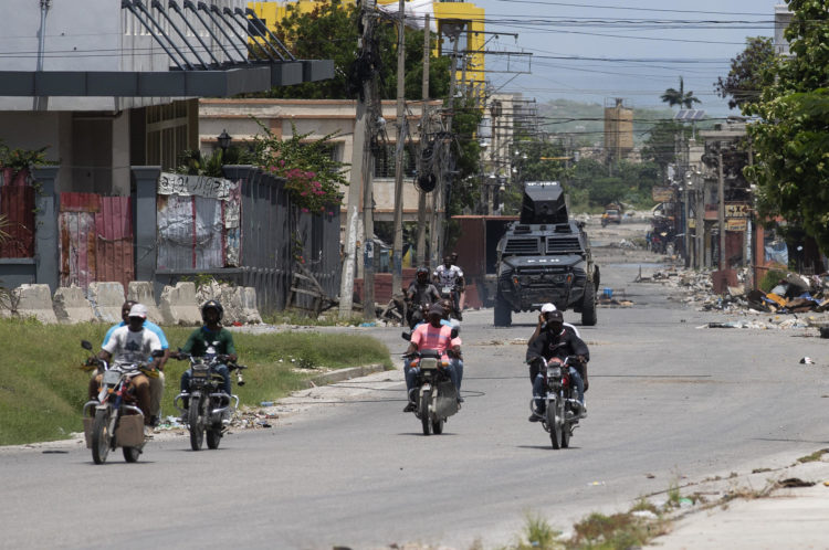 Motoristas transitan por la calle Paul VI mientras son escoltados por camiones blindados de la Policía Nacional, este 27 de mayo de 2024 en Puerto Príncipe (Haití).EFE/ Orlando Barría